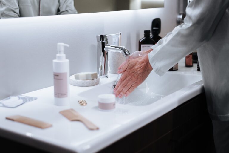 Close-up of a man washing hands in a modern bathroom, emphasizing hygiene and cleanliness.