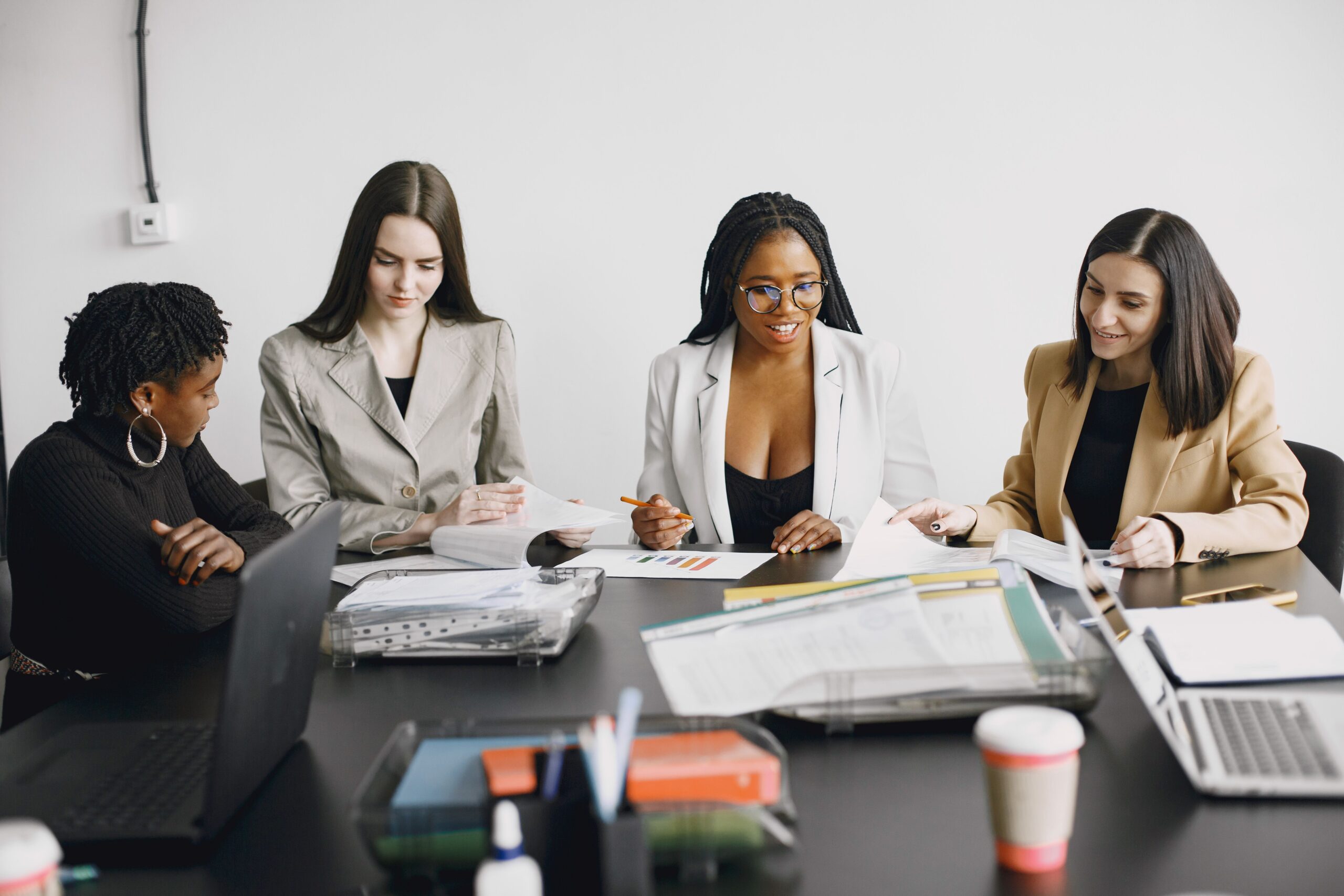 A diverse group of women engaged in a collaborative office meeting, discussing documents.